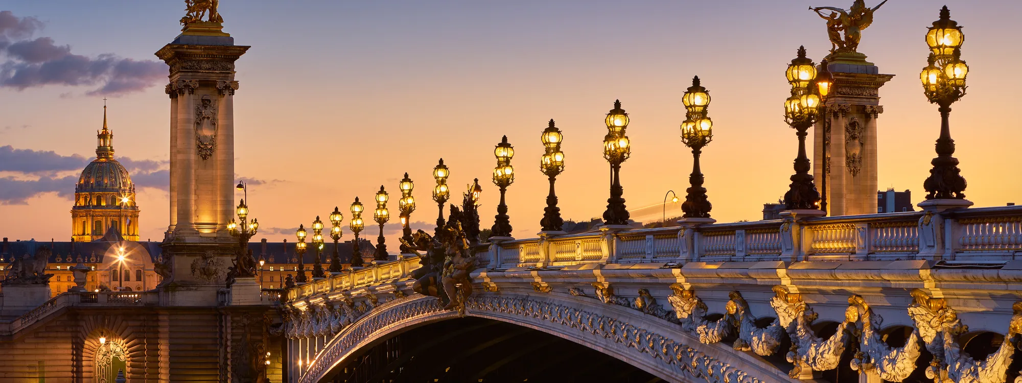 Le pont Alexandre III et ses lampadaires au crépuscule, dôme des Invalides en arrière-plan