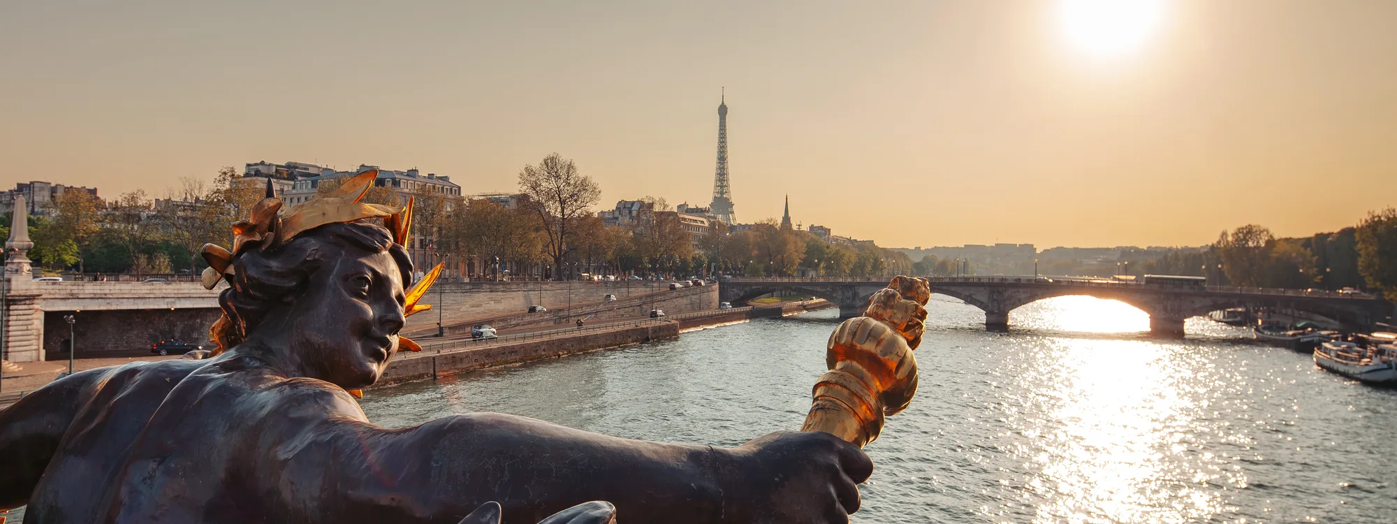 Statue dorée du pont Alexandre III, la Tour Eiffel en arrière-plan au coucher du soleil